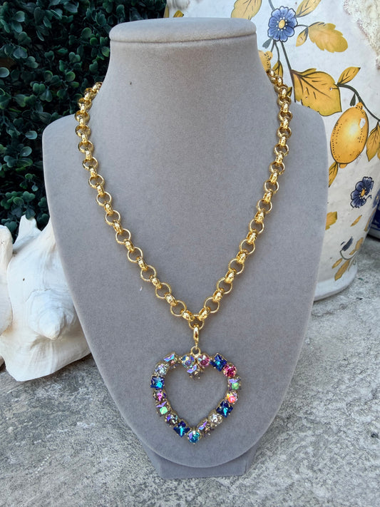 heart shaped pendant with round and square crystals in blue tones on a gold necklace