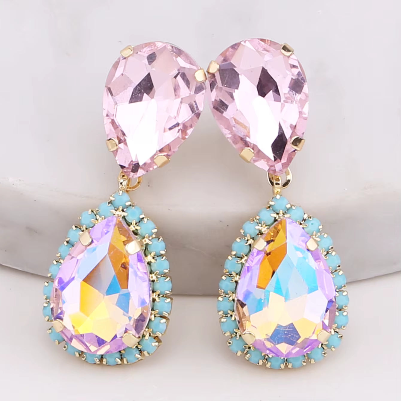Pair of earrings with pink and multicolored gemstones on a light background