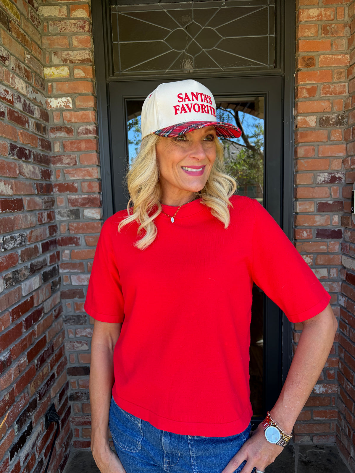 A beige baseball cap that says Santa’s favorite in red with a red holiday plaid bill