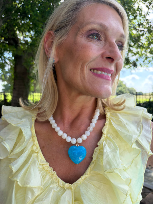 opaque white beaded strand necklace with blue resin heart pendant
