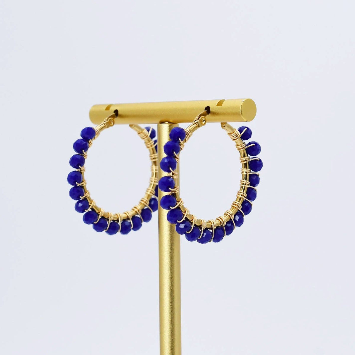 Gold hoop earrings with small faceted blue beads along the outer edge