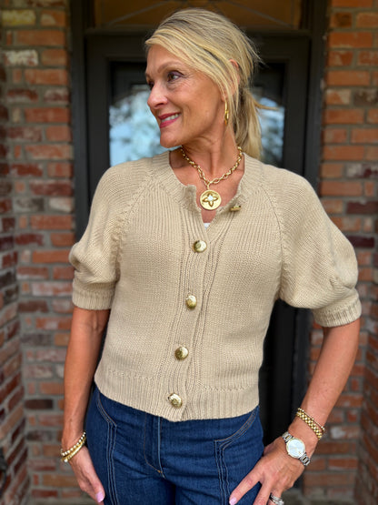 an acrylic tan short sleeve button down cardigan with hammered gold button detail and an elevated, gathered sleeve. 