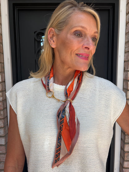 colorful orange tone scarf around the neck with gold horsebit metal piece