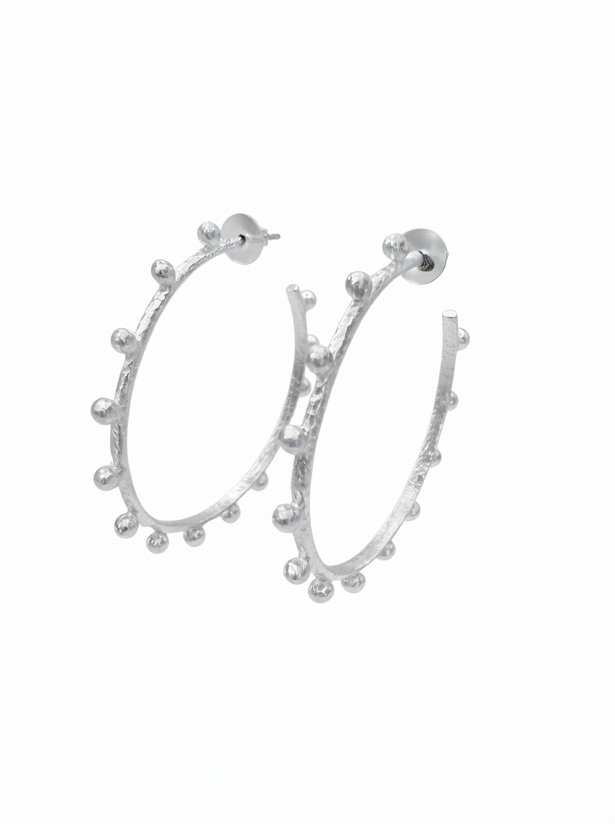 A pair of silver hoop earrings with a textured finish and small bead-like details along the outer edge, shown against a plain white background.
