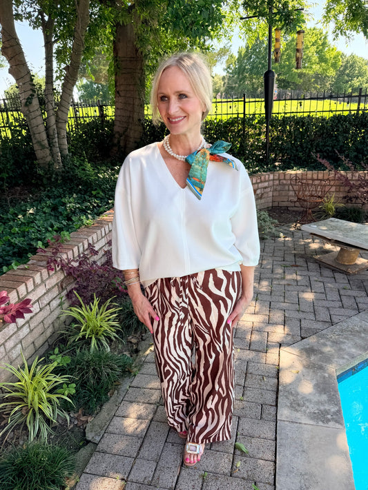 pearl strand with color scarf necklace wearing an off white top and zebra pants