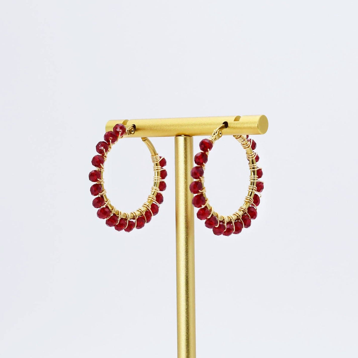 A pair of gold hoop earrings with red beaded detailing