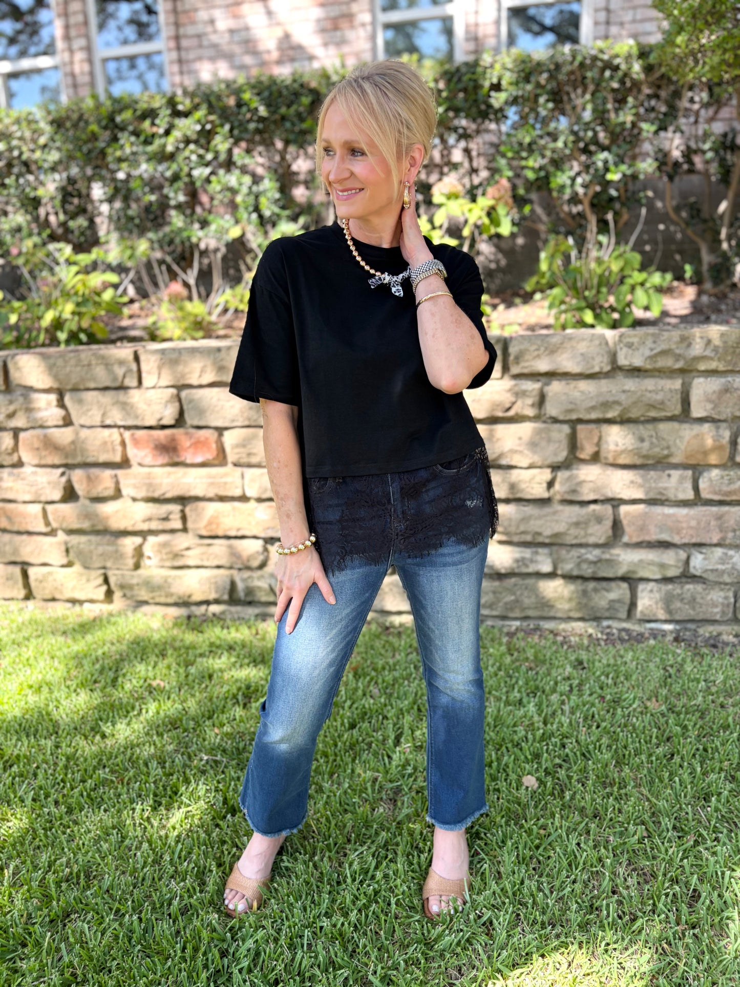 a woman in black tee that is short sleeved and trimmed in black lace with denim