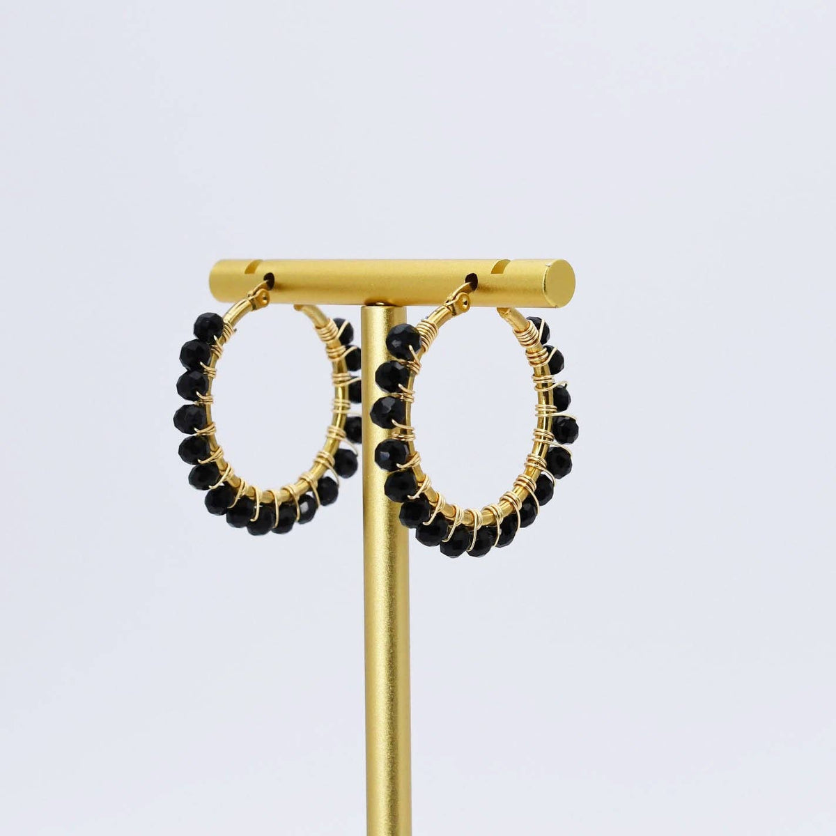 Gold hoop earrings with a row of small black beads along the outer edge
