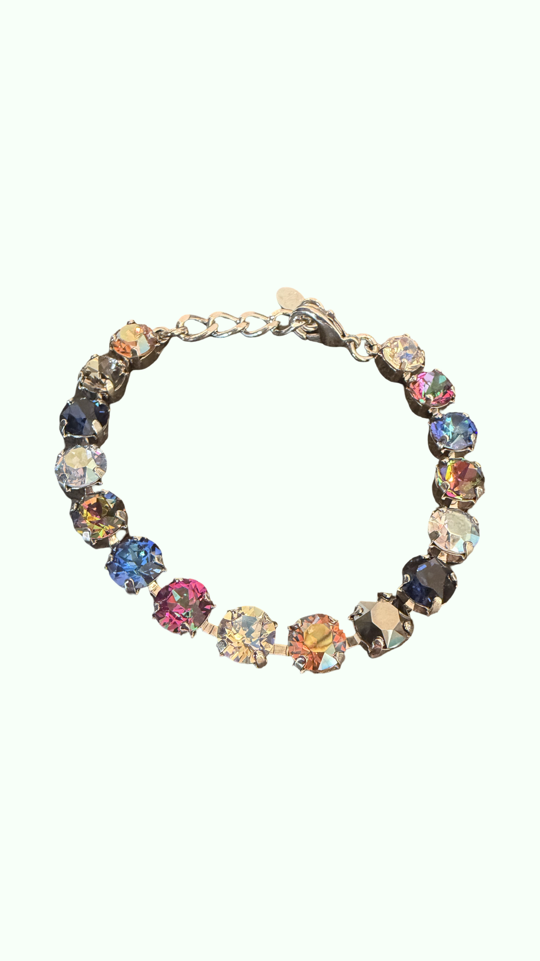 A gold-tone chain bracelet with multiple round, iridescent faceted rhinestones in assorted colors, displayed on a solid pale mint green background.
