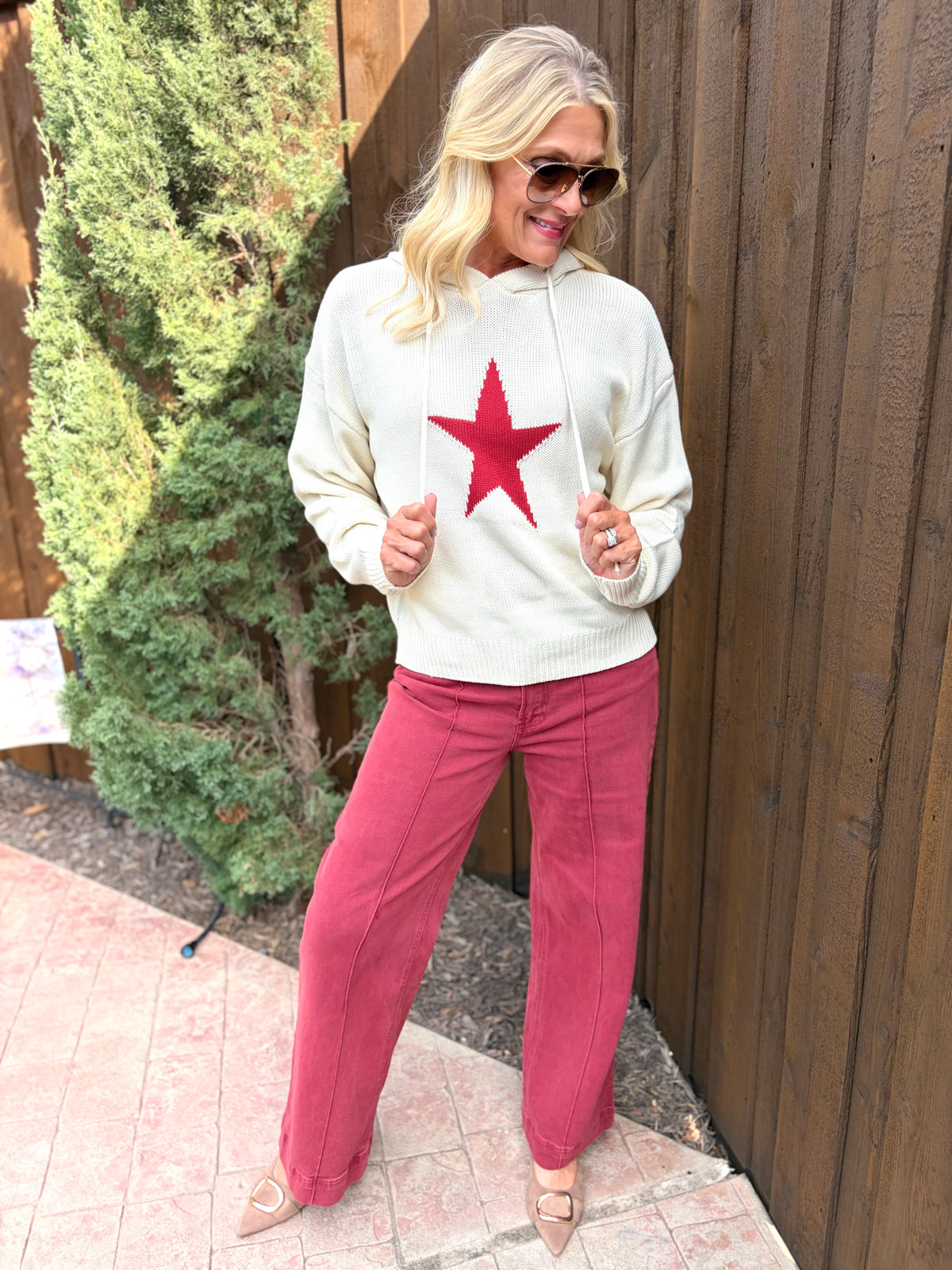 A cream pullover sweater with cranberry red star on front with hoodie on back 