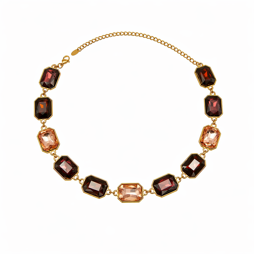 A gold chain necklace featuring alternating rectangular faceted gemstones in deep burgundy and soft peach, displayed on a clean white background.