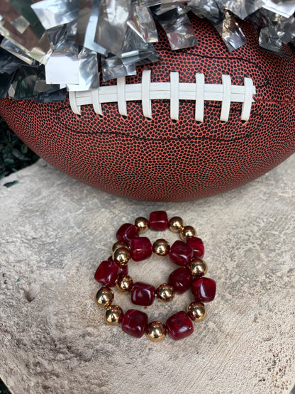 A beaded stretch bracelet with deep  burgundy/crimson faceted beads and metallic gold spacer beads