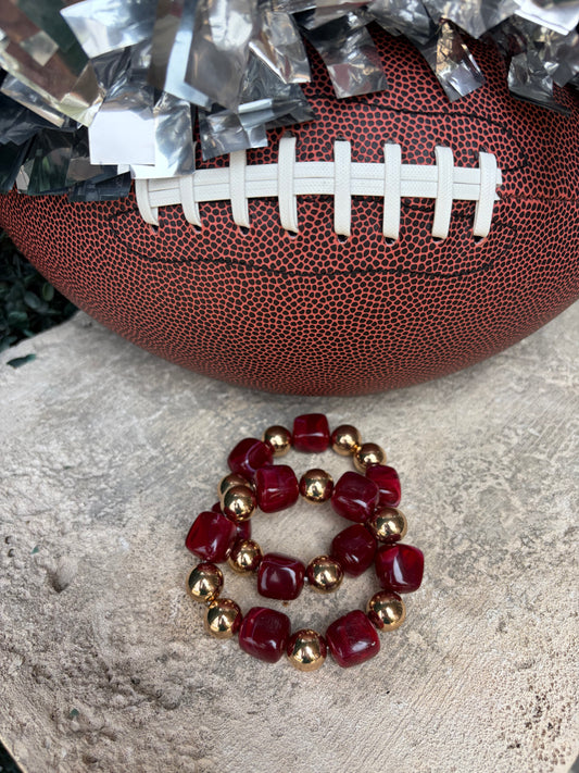 A beaded stretch bracelet with deep  burgundy/crimson faceted beads and metallic gold spacer beads