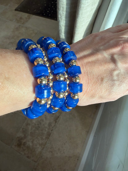 5 strand stretch bracelet set that is 3 blue beads with small round gold beads alternated and 2 strands of just small gold beads. This is water resistant 