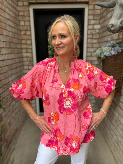pink top with orange and pink, white flowers with ruffle collar pictured with white denim