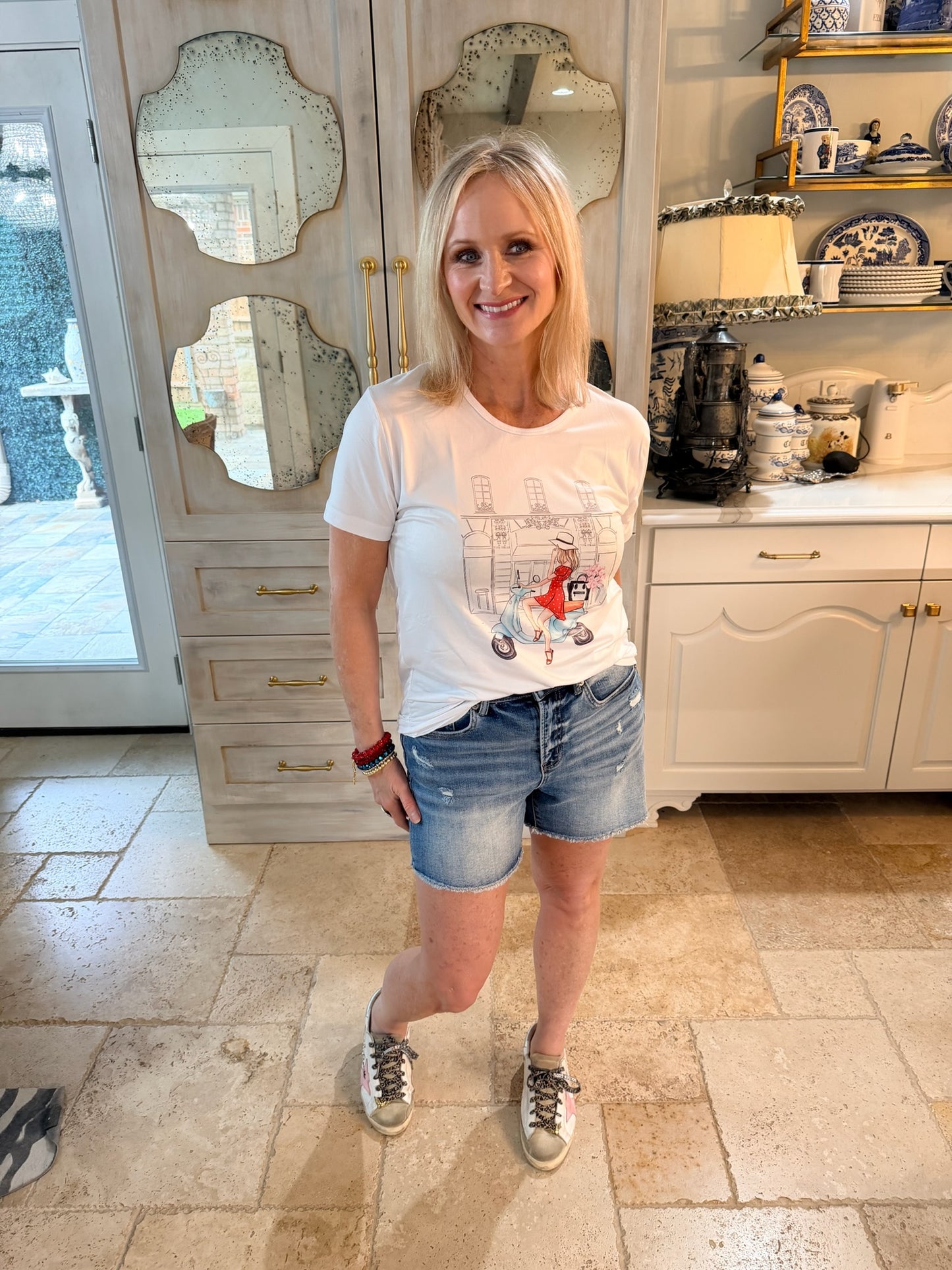 woman wearing graphic tee of girl on a vespa scooter with denim shorts
