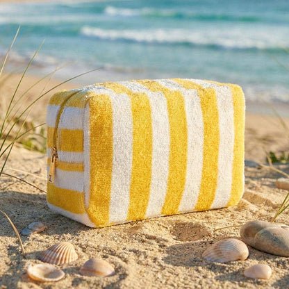 Yellow and white striped pouch on a sandy beach with ocean in the background