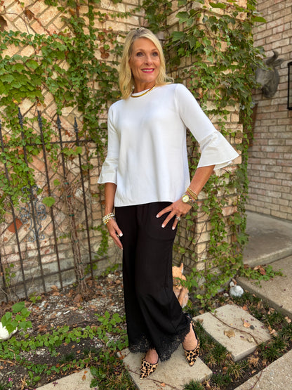 a sikly black pant with lace detail at hem paired with a white light weight sweater top with poplin detail on cuff