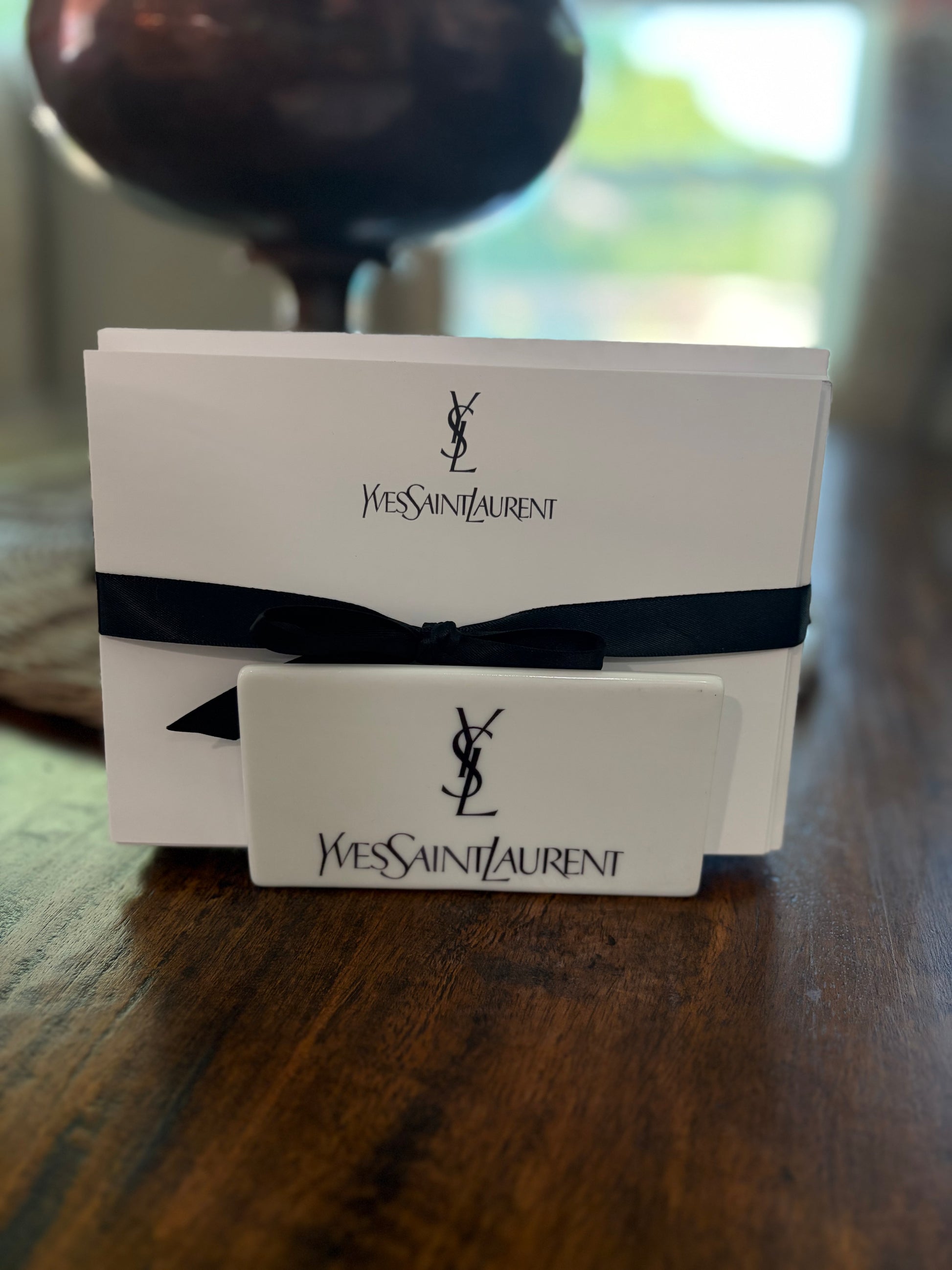 A fashion gift card set on a dark wooden table, featuring white cards with the black logo and name, wrapped in ribbon