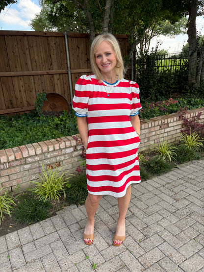 Red and white striped, cotton stretch dress that is knee length. Blue and white varsity ruffle detail on sleeve and crew neckline