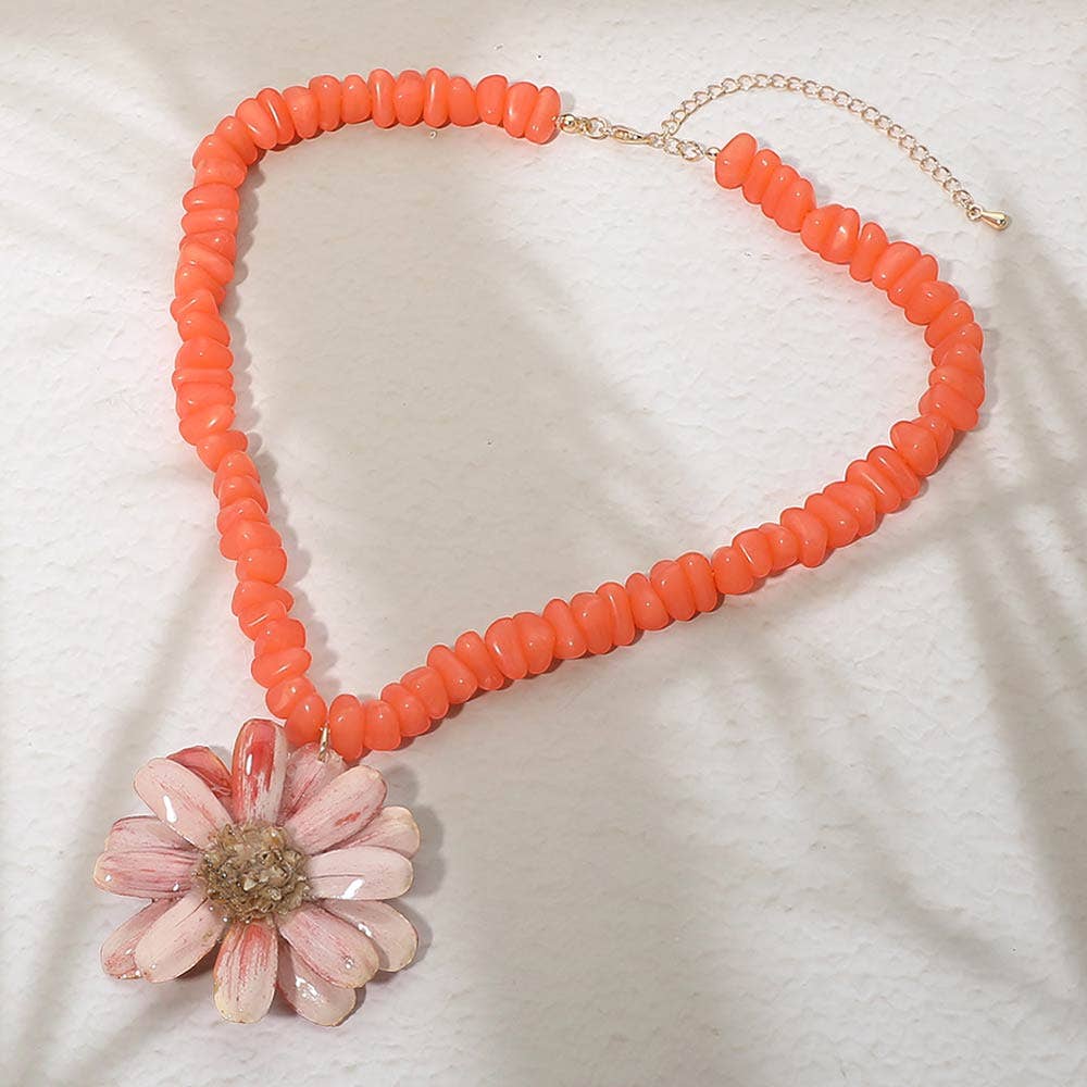 orange beaded necklace with pink flower pendant