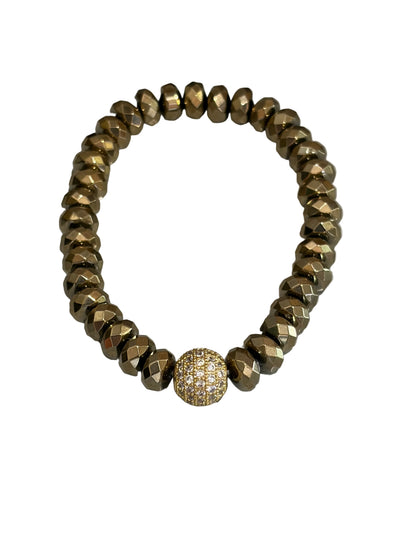 A stretch bracelet made of faceted metallic gold beads with a single round pavé-set gold bead accent in the center, displayed on a light gray surface.