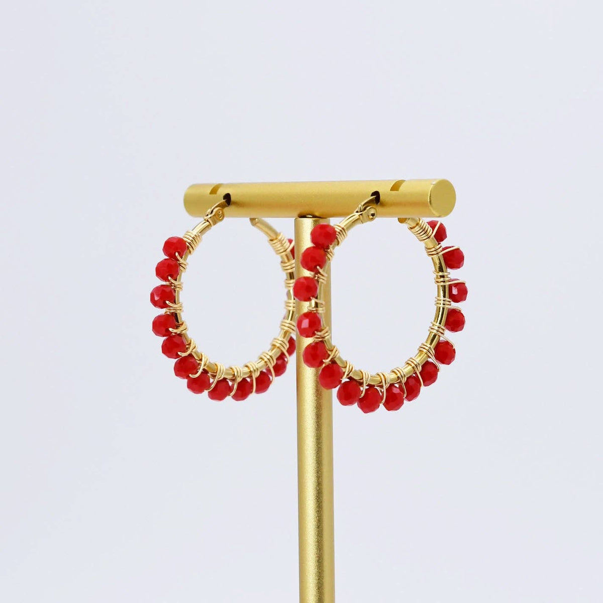 Gold hoop earrings with small red beads along the outer edge