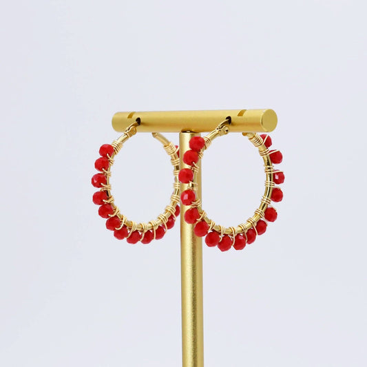 Gold hoop earrings with small red beads along the outer edge