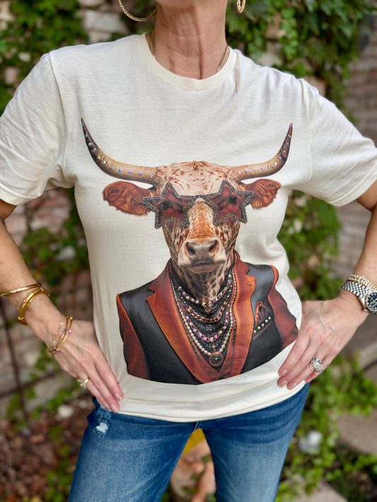 a woman in cream tee with a longhorn graphic with star sunglasses, rhinestone accents and in an orange and black jacket