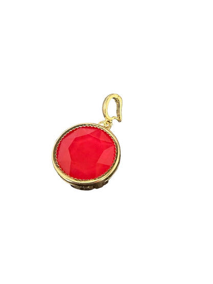 A gold pendant charm featuring a round, faceted red gemstone