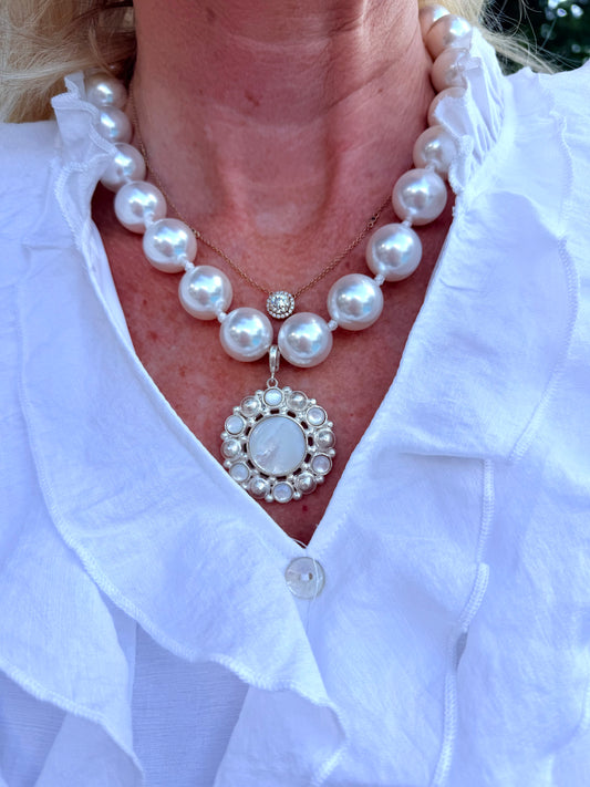a magnetic closure strand of round, white beaded pearl necklace with mother of pearl and silver medallion charm.