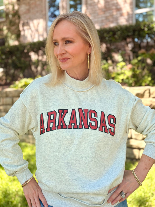  light heather gray mock neck sweatshirt with 'ARKANSAS' printed in red and black arched letters across the chest. Reversible. The initials AR is on the other side