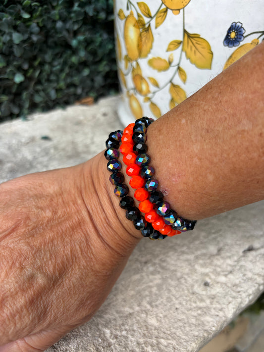 3 bead stretch bracelet set featuring on orange bracelet with 2 shimmering, midnight blue bracelets. 
