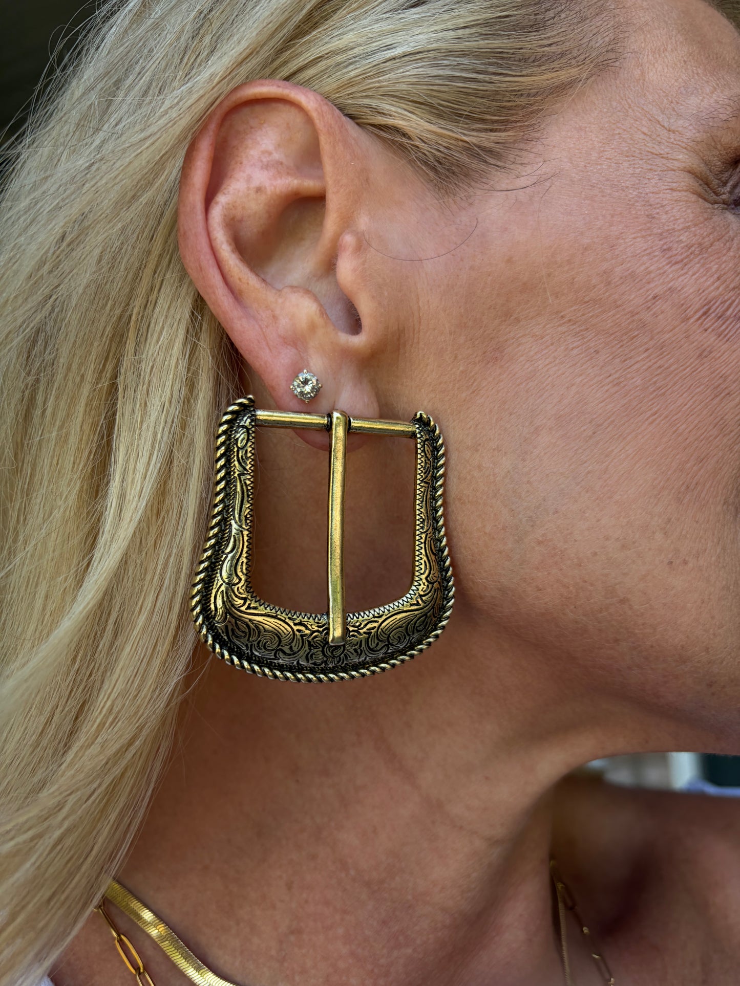an antique, brass gold tone post earring of a unique belt buckle design