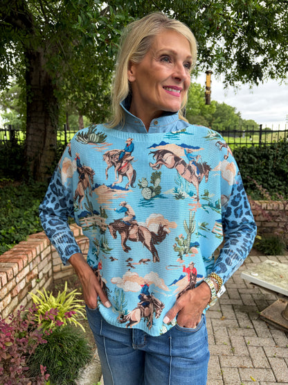 Woman wearing a blue patterned Italian knit sweater with cowboy and horses on it. leopard print  long sleeves