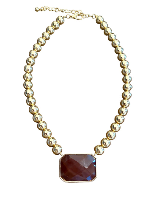 A gold beaded necklace with a faceted rectangular dark brown gemstone pendant, 