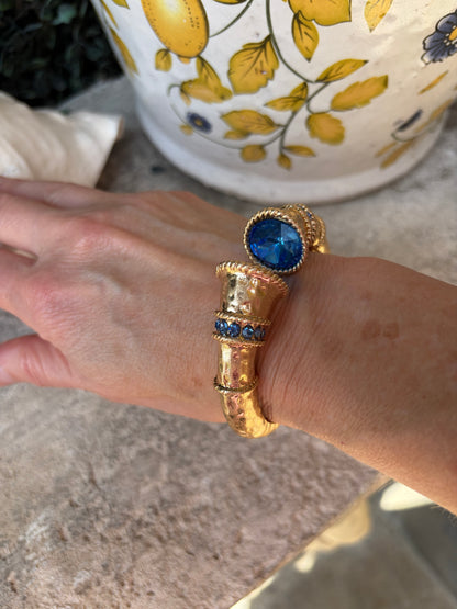 Gold , water resistant bangle bracelet with blue gemstones on a wrist