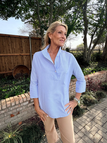woman wearing blue and white striped, long sleeve blouse. V neck with faux collar.  also in khaki crop pant.