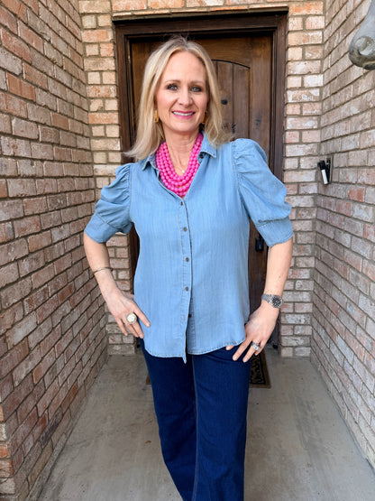 woman wearing a chambray, puff , short sleeve button down top with denim jean. 
