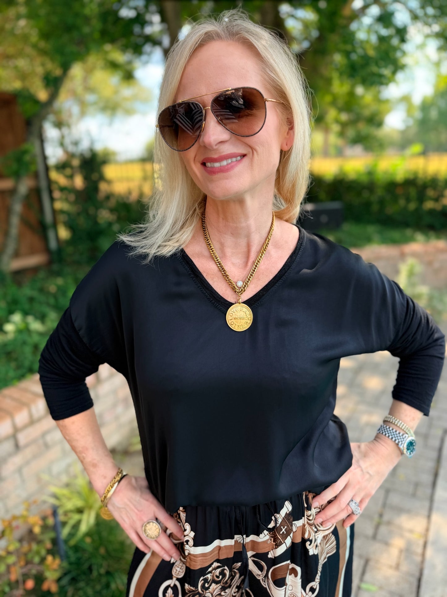a Black v neck long sleeve top with small bead detail on neckline. front is silky feel with sleeves and back a cotton tshirt style
