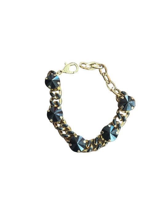 gold link bracelet with black enamel details on link with 5 black stones that sit on link in gold prongs