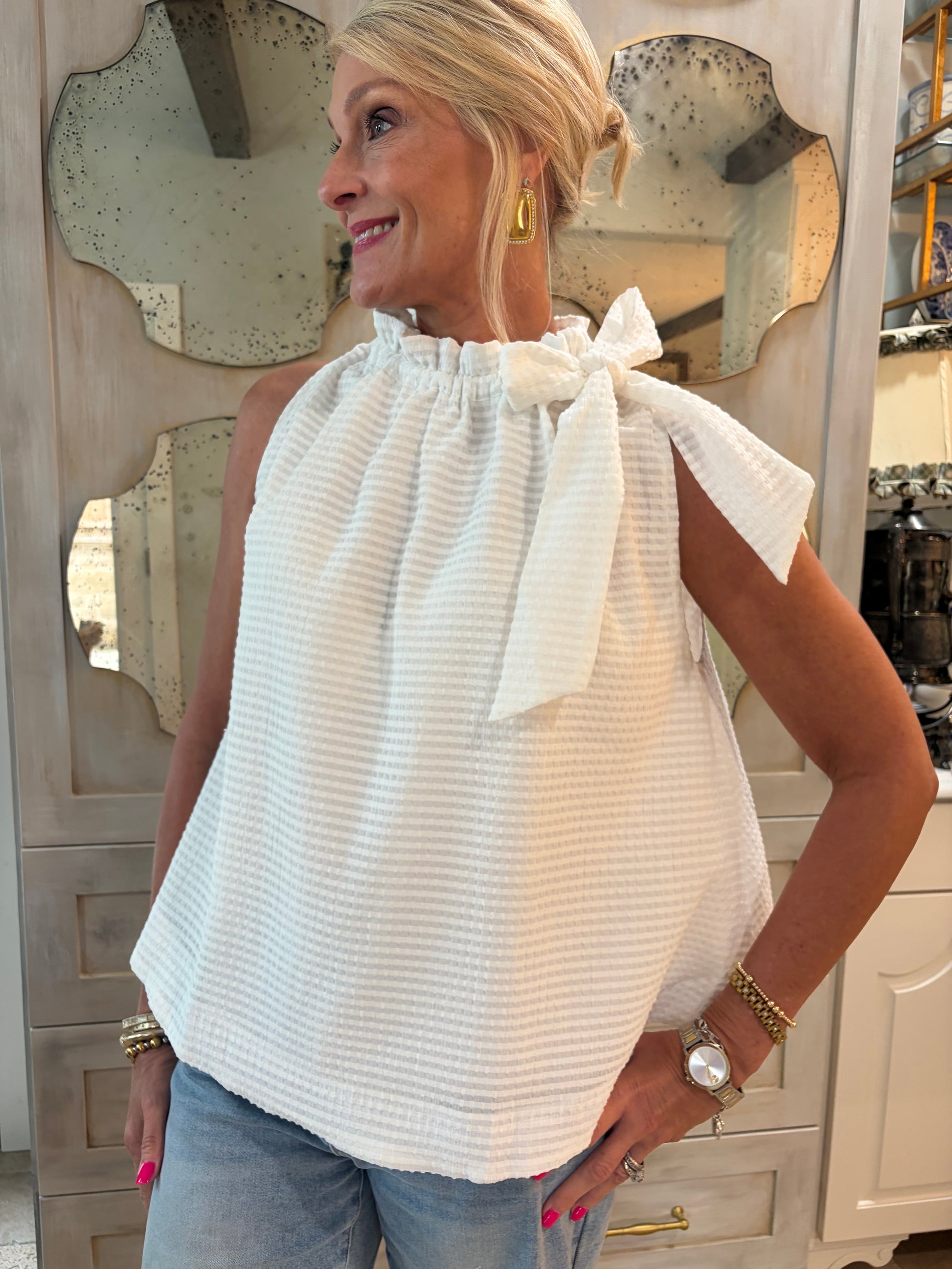 woman wearing white sleeveless whimsy top with rufffle tie neck 