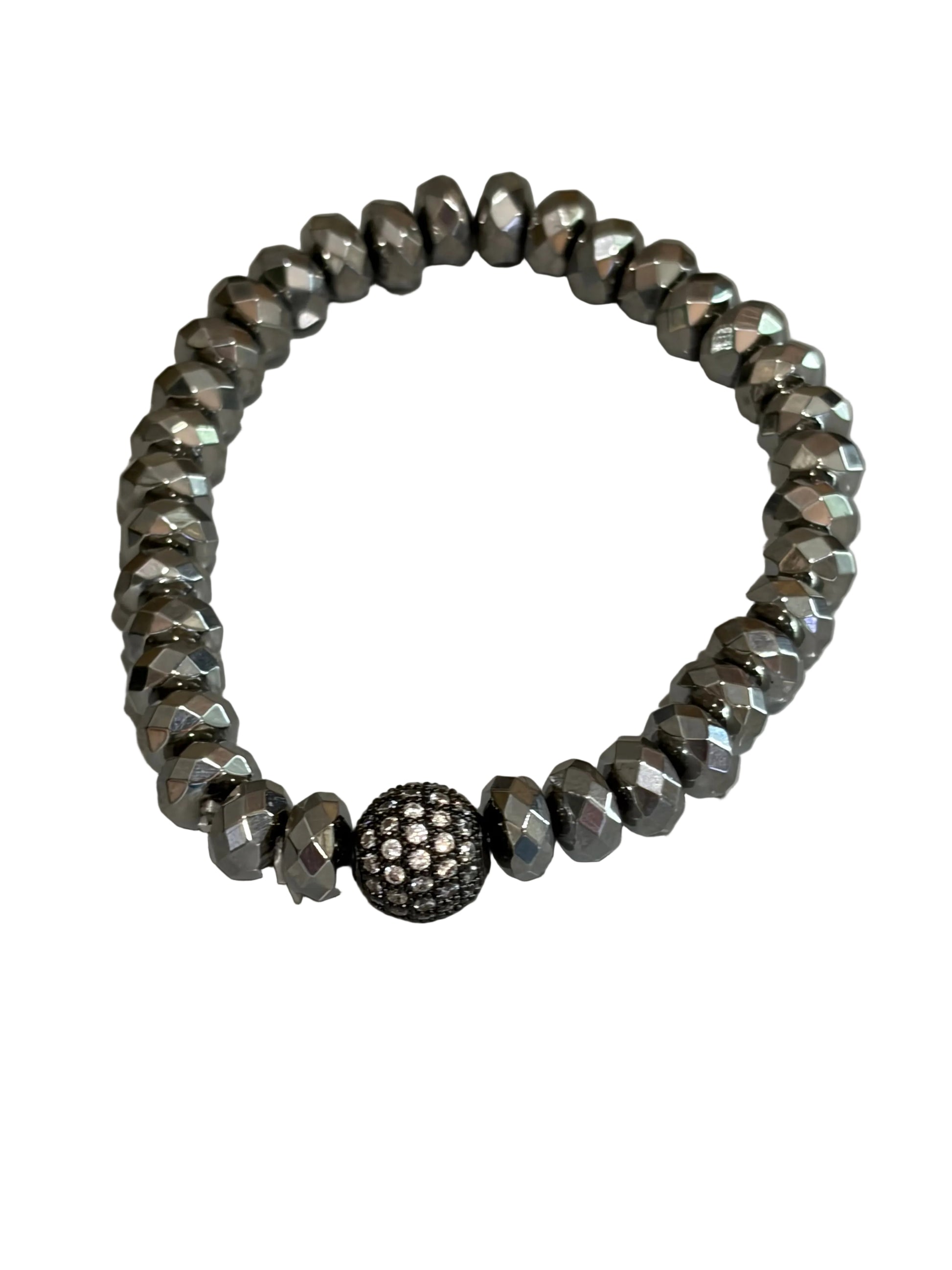 A beaded stretch bracelet made of faceted metallic gray beads, featuring a central round dark metallic bead covered in small clear stones, photographed on a light gray surface.
