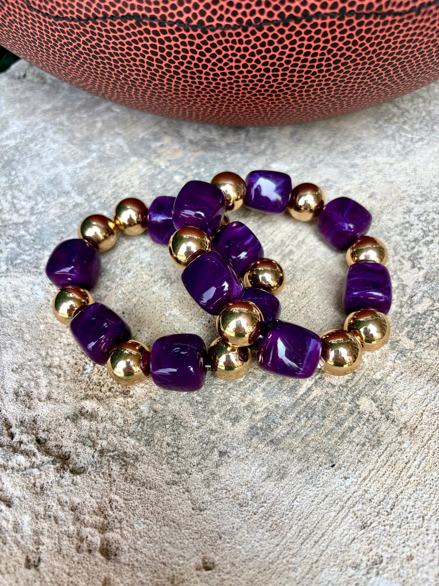Two beaded stretch bracelets with glossy purple cube beads and shiny gold round beads