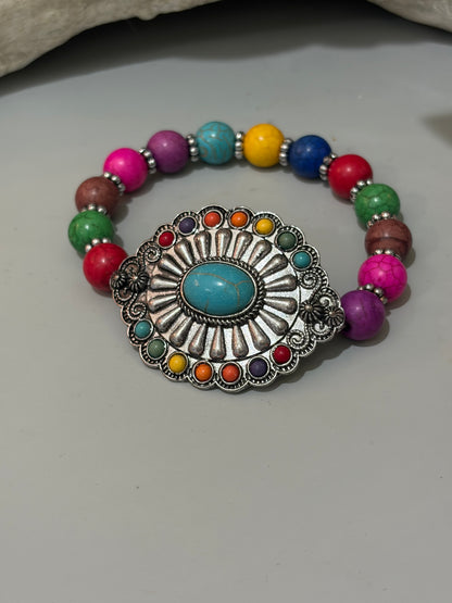 silver concho bracelet with turquoise center stone and smaller stones in color around it. Colorful beads that make up the stretch band