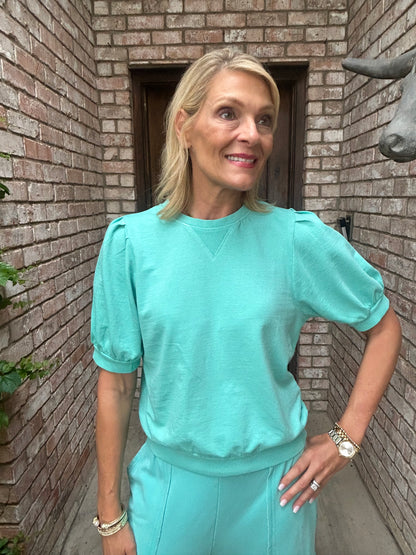 Woman in a turquoise pullover, short sleeve, crew neck.