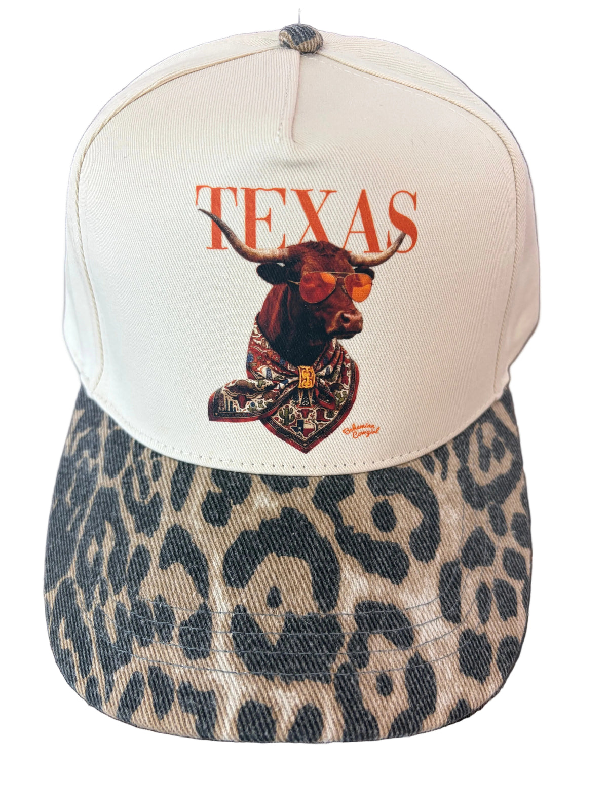 beige baseball cap with word TEXAS in burnt orange with a deep orange longhorn wearing sunglasses that are shaded orange with texas themed bandana around his neck. Bill of hat is a muted leopard print