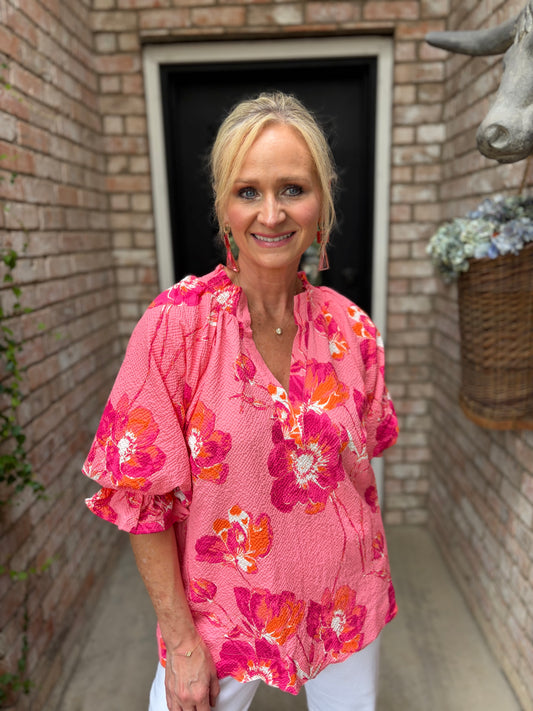 pink top with orange and pink, white flowers with ruffle collar pictured with white denim