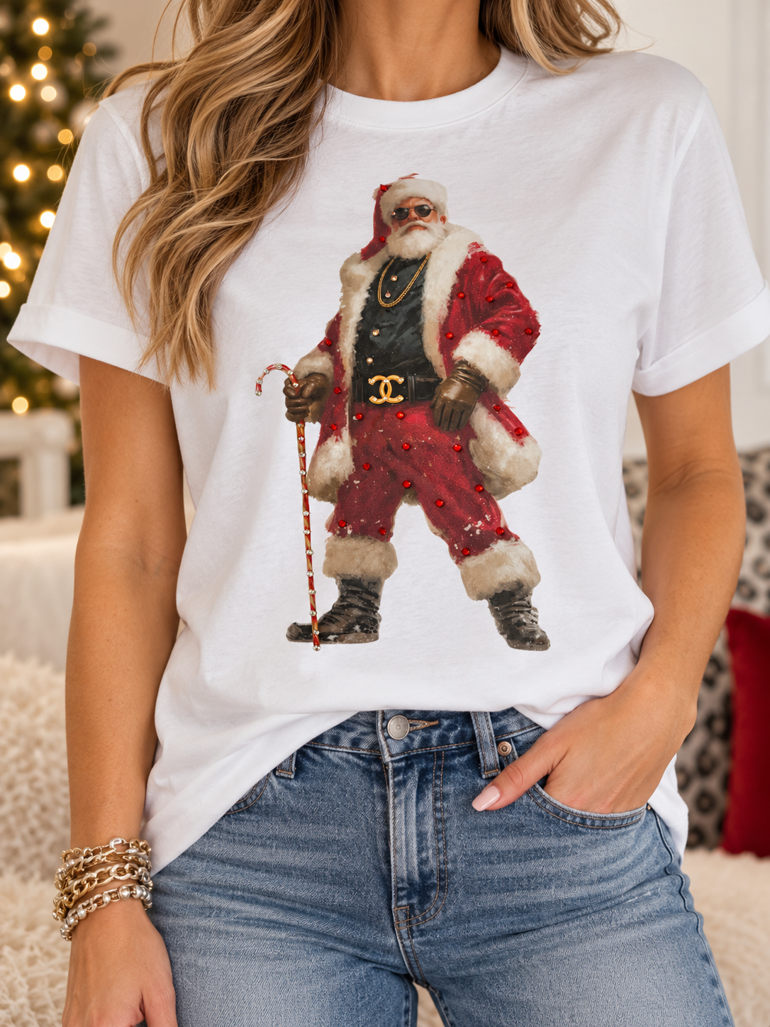 A woman wearing a white short-sleeve graphic T-shirt featuring a vintage-style illustration of Santa Claus in a red suit with sparkle bling , glasses and fun belt with white fur trim, paired with blue jeans.