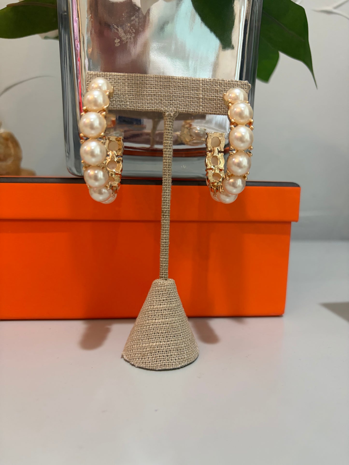 Pearl and gold earrings on a stand with an orange box in the background